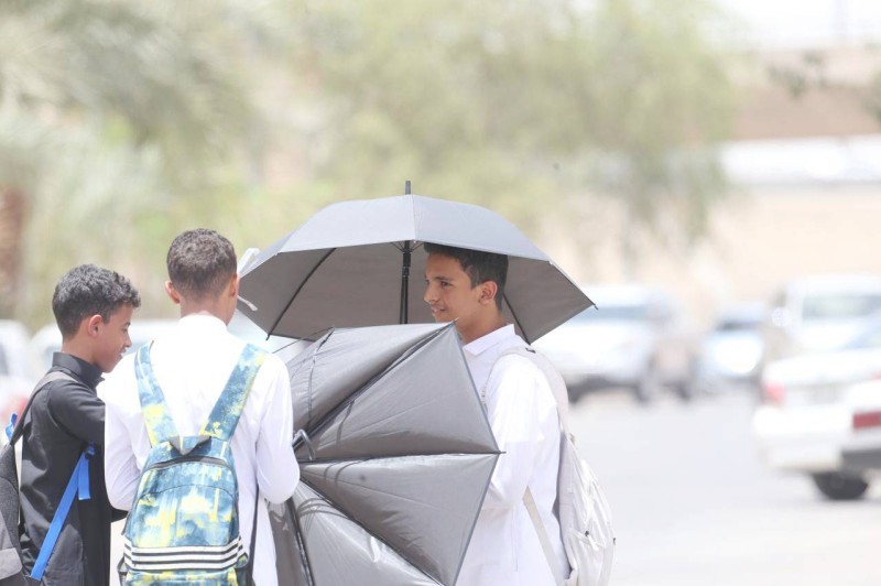 



طلاب لجأوا إلى الواقيات الشمسية لحمايتهم من حرارة الطقس.  (تصوير: مديني عسيري)